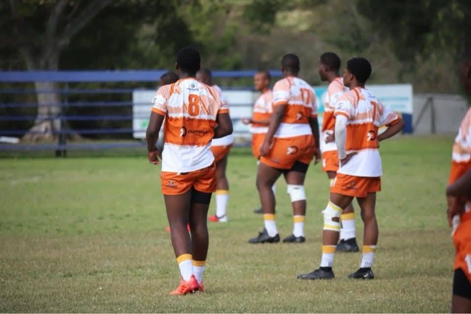 Academy players in orange and white kit waiting during a break in play